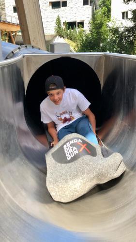 a young boy is sitting in a play tunnel with a skateboard at Rancho Laaxdeluxe in Laax