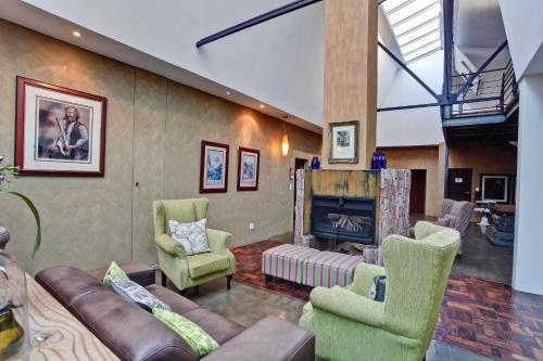 ein Wohnzimmer mit einem Sofa, Stühlen und einem Kamin in der Unterkunft Bramasole Boutique Hotel in Magoebaskloof