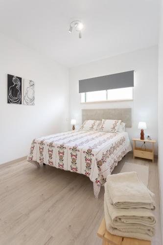 a white bedroom with a bed and a table at Quinta dos Passarinhos in Nadadouro