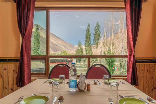 a table with a view of a mountain through a window at Echor Mud Huts Tabo, Spiti Valley in Kaza