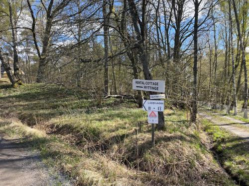 a sign on a road in a field with trees at Fishermans cabin in Myttinge