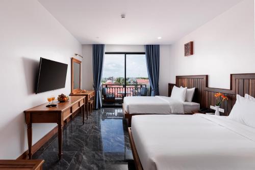 シェムリアップにあるTwo Seasons Siem Reap Hotelのベッド2台とテレビが備わるホテルルームです。