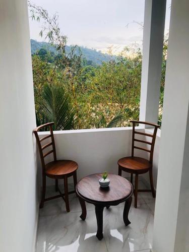 a porch with two chairs and a table and a window at Kandy River Garden in Kandy