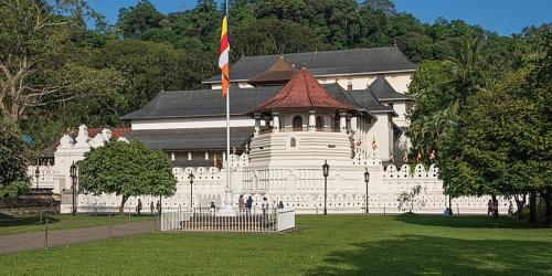 un grand bâtiment blanc avec drapeau dans un parc dans l'établissement Kandy River Garden, à Kandy
