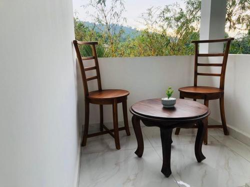 Kandy River Garden في كاندي: كرسيين وطاولة أمام النافذة