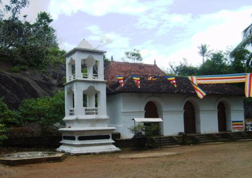 a white building with a clock tower in front of it at Kandy River Garden in Kandy