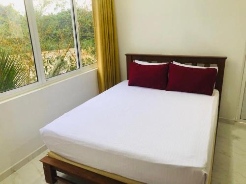 a bed with red pillows in a room with windows at Kandy River Garden in Kandy