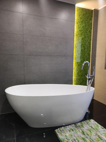 a white tub in a bathroom with a green wall at Pensjonat Klimat Bircza in Bircza