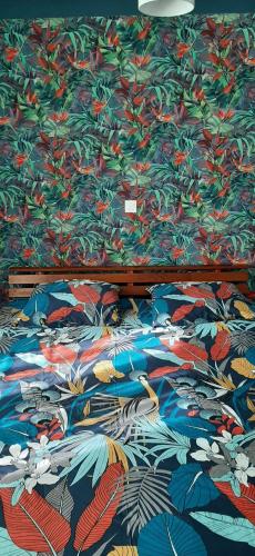 a bed with a colorful comforter on it at Kaz papaye in Saint-Pierre
