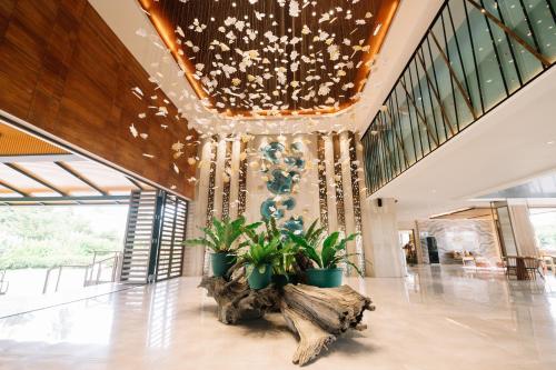 a lobby with a chandelier and plants on the floor at Nouveau Resort in Mambajao