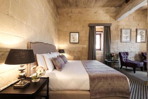 um quarto com uma cama e uma mesa com um candeeiro em Cesca's Boutique Hotel em Xlendi