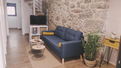 uma sala de estar com um sofá azul e uma parede de pedra em Casita Barrena em Bueu