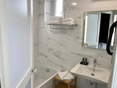 a bathroom with a tub and a sink and a mirror at Hôtel Coeur De Loire in Nantes