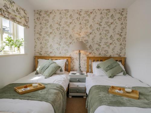 two twin beds in a room with wallpaper at Columbine Cottage in Ambleside