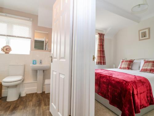 a bedroom with a bed and a sink and a toilet at Woolpack Cottage in Stow on the Wold