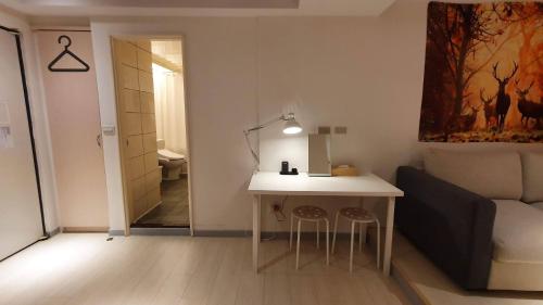 a room with a desk and a bed and a table and stools at Yomi Hotel - ShuangLian MRT in Taipei
