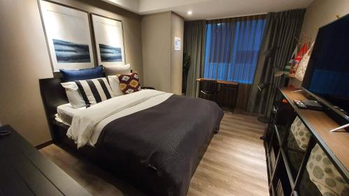 a bedroom with a bed and a flat screen tv at Yomi Hotel - ShuangLian MRT in Taipei