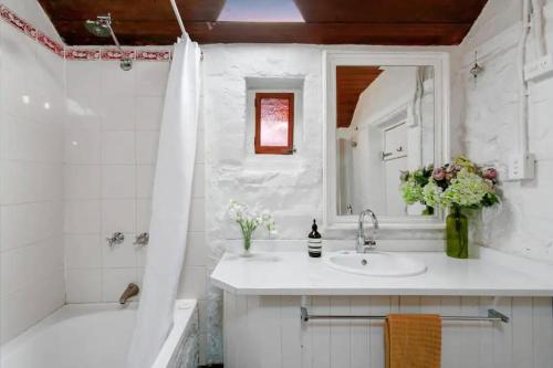 a bathroom with a sink and a tub and a mirror at Hamptons Historic Guest House in Littlehampton