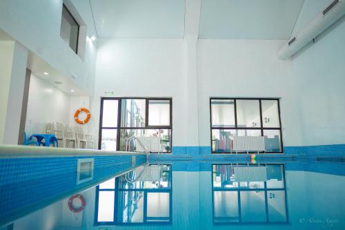 a swimming pool in a building with windows and a pool at Hotel Hera in Predeal