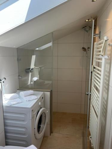 y baño con lavadora y espejo. en Apartment Wendelsteinblick - Wohnen auf Zeit - Homeoffice - Balkon mit Bergblick- buchbar ab 28 Nächte en Schliersee