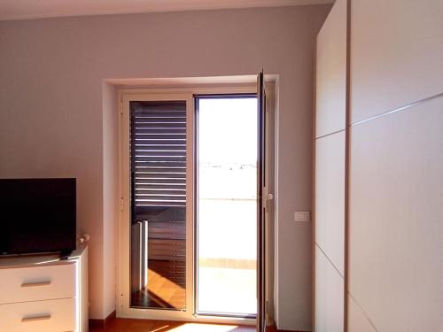 Pokój z przesuwnymi szklanymi drzwiami i oknem w obiekcie Appartamento luminosissimo con vista panoramica w mieście Marina di Cerveteri