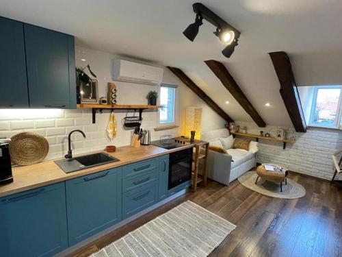 a kitchen with blue cabinets and a living room at Condo in town centre in Rijeka