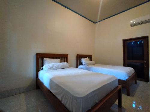two twin beds in a room with a window at Sari Laut in Gili Meno