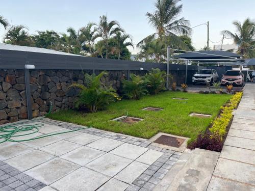 a yard with a stone wall and a grass field at Coastal View Apartments in Grand Baie