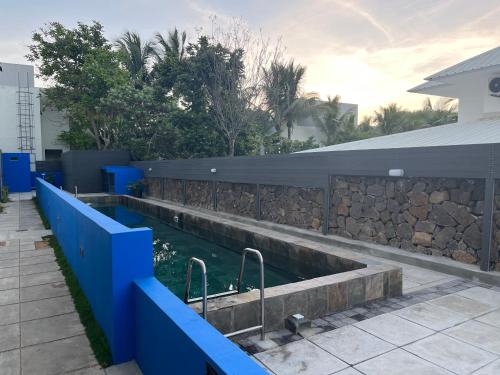 a swimming pool with a blue fence and a stone wall at Coastal View in Grand Baie