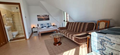 a bedroom with a couch and a bed and a bathroom at Villa Kapitańska in Kołobrzeg