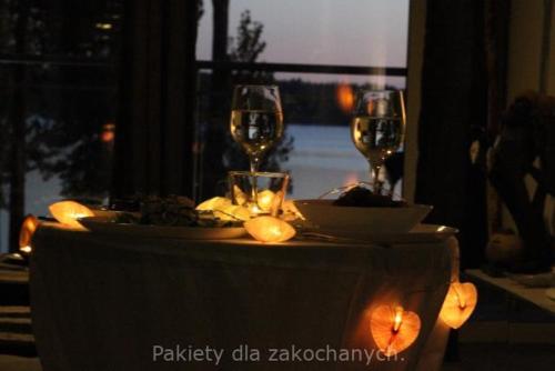 a table with two glasses of wine on top of it at MIŁOŚĆ ma swój adres - ZMYSŁOWE apartamenty z JACUZZI dla Dwojga in Ełk