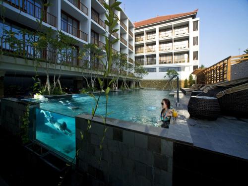 a woman in a swimming pool in a building at Grand Zuri Kuta Bali in Kuta