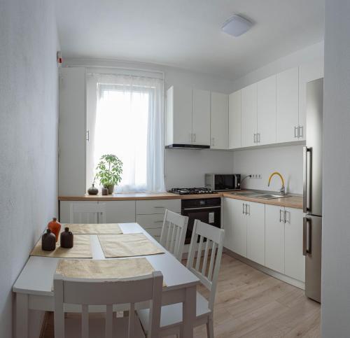 a kitchen with white cabinets and a table and chairs at Solomon Apartments Ap 4 in Sângeorgiu de Mureș