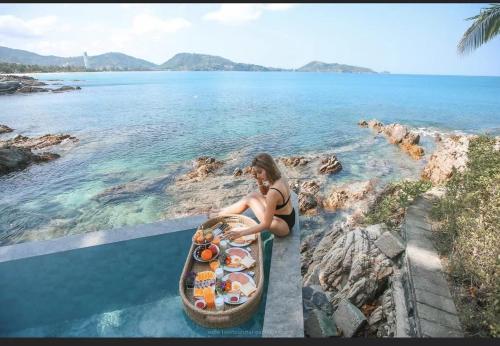a woman sitting next to a boat in the water at patong sunset villa Phuket in Patong Beach
