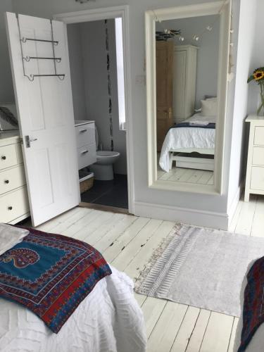 1 dormitorio con espejo, 1 cama y baño en Shoreline, en St Ives
