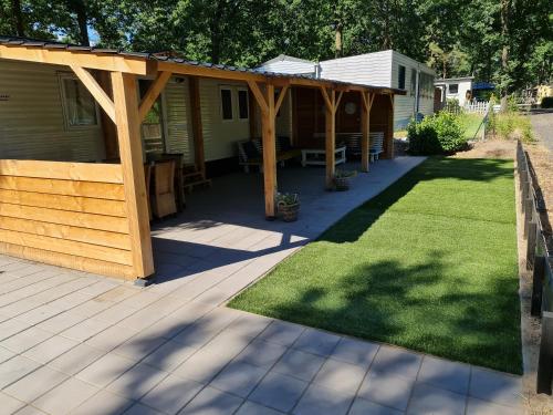 eine Pergola über einer Terrasse mit Gras in der Unterkunft Chalet Casablanca, totaal 80m2 met veel comfort op fantastisch 5-sterren vakantiepark! in Sevenum