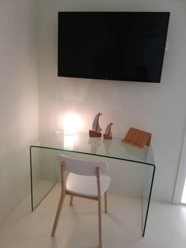 a glass desk with a chair and a television on a wall at Tarik Home live traditional in Ano Syros