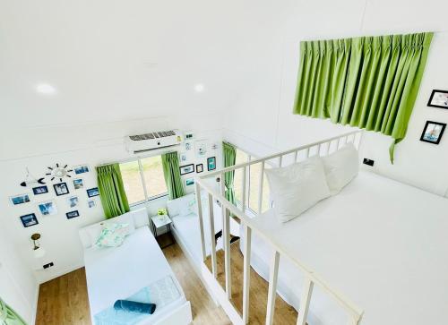 a white room with a staircase and green curtains at Thirty Tree Garden House in Chumphon