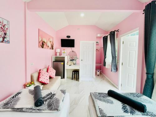 a pink room with a couch and a desk at Thirty Tree Garden House in Chumphon