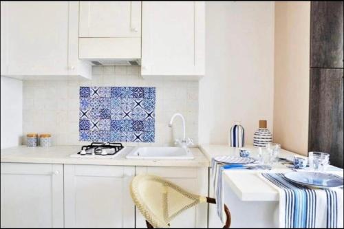 a kitchen with white cabinets and a blue and white tiles at Appartamento Borgo Rio Favara in Ispica