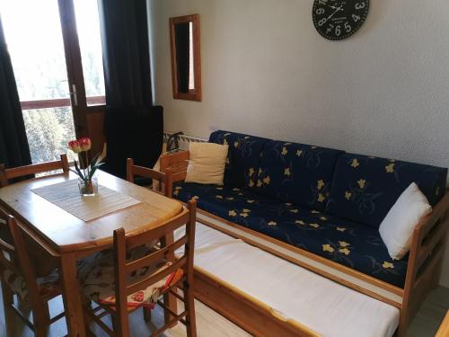 a living room with a blue couch and a table at Appartement Edelweiss Chamrousse vue sur Recoin La Croix de Chamrousse Grenoble in Chamrousse