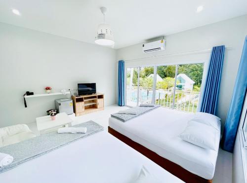 a white bedroom with two beds and a window at Thirty Tree Garden House in Chumphon
