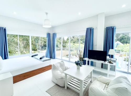 a white living room with blue curtains at Thirty Tree Garden House in Chumphon