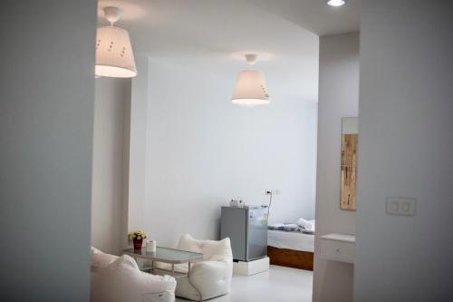 a white living room with a table and a refrigerator at Thirty Tree Garden House in Chumphon