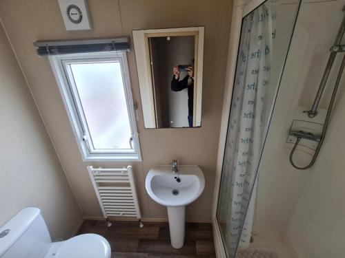 a person taking a picture of a bathroom with a sink at Deluxe 3 Bedroom Caravan with extra en-suite North Shore in Skegness