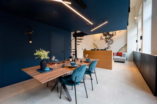 comedor con paredes azules y mesa y sillas de madera en Atypique LOFT Mons City Center, en Mons