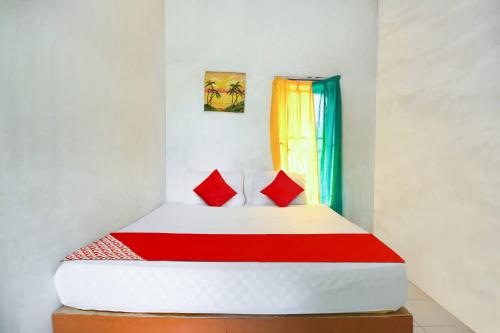 uma cama com duas almofadas vermelhas num quarto em OYO 91051 Penginapan Pondok Ratu 354 em Pontianak