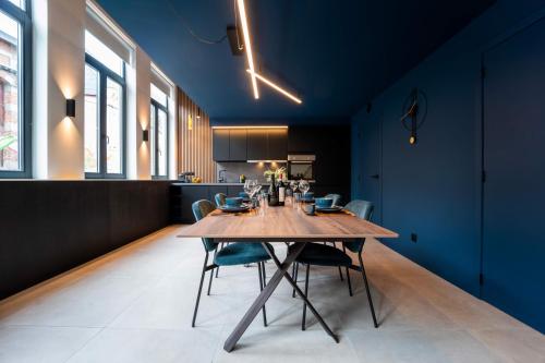 Atypique LOFT Mons City Center في مون: غرفة طعام مع طاولة خشبية وجدران زرقاء