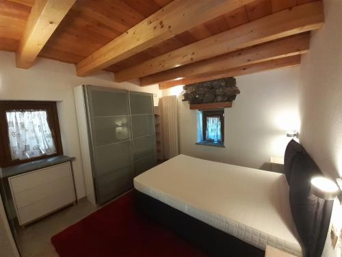 Un dormitorio con una cama blanca en una habitación con techos de madera. en Acero Rosso en Champdepraz