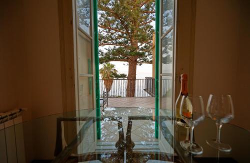 a glass table with a bottle and two wine glasses at Maison Canopée in Messina